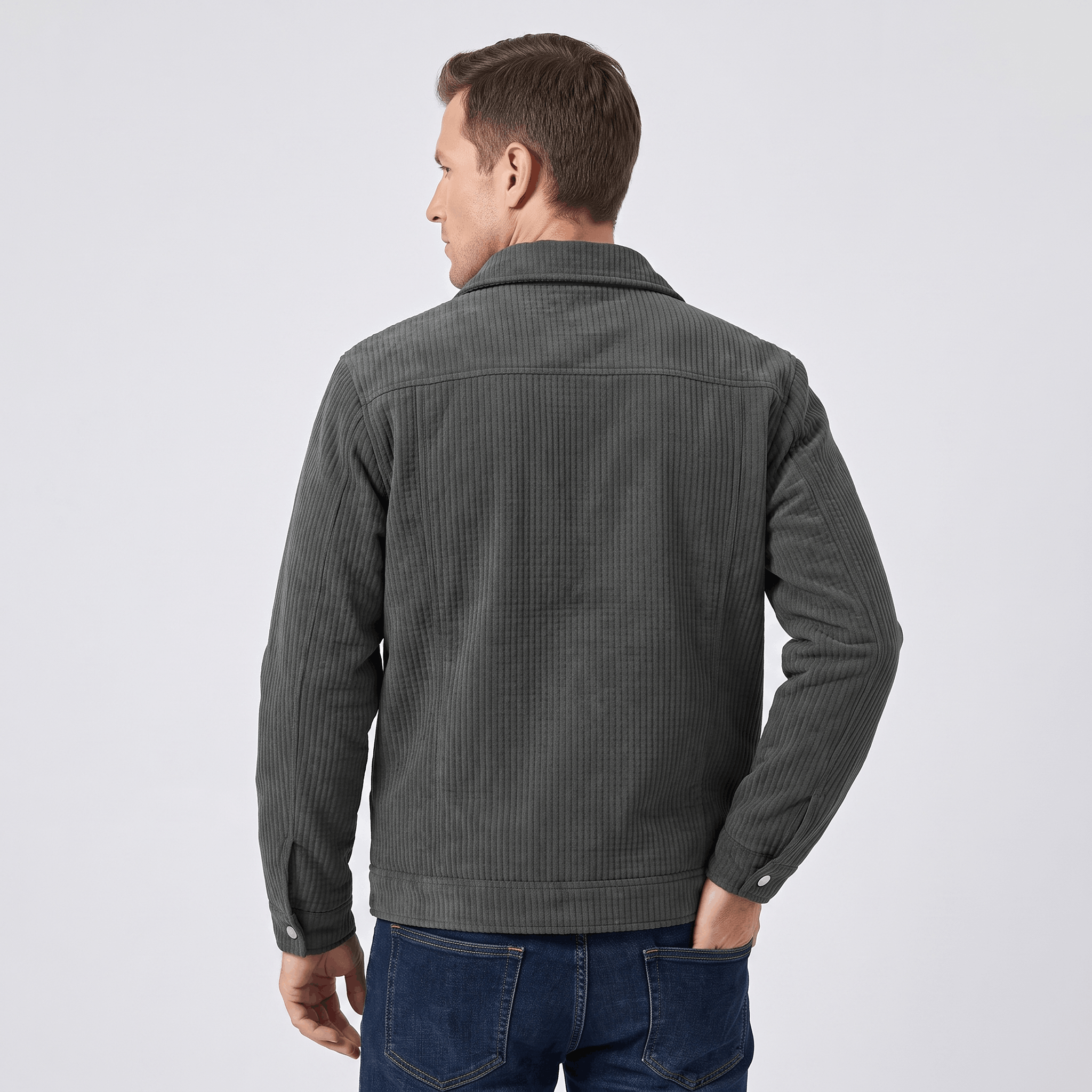 Dark charcoal quilted corduroy trucker jacket with a structured collar and snap-button cuffs worn over dark blue jeans.