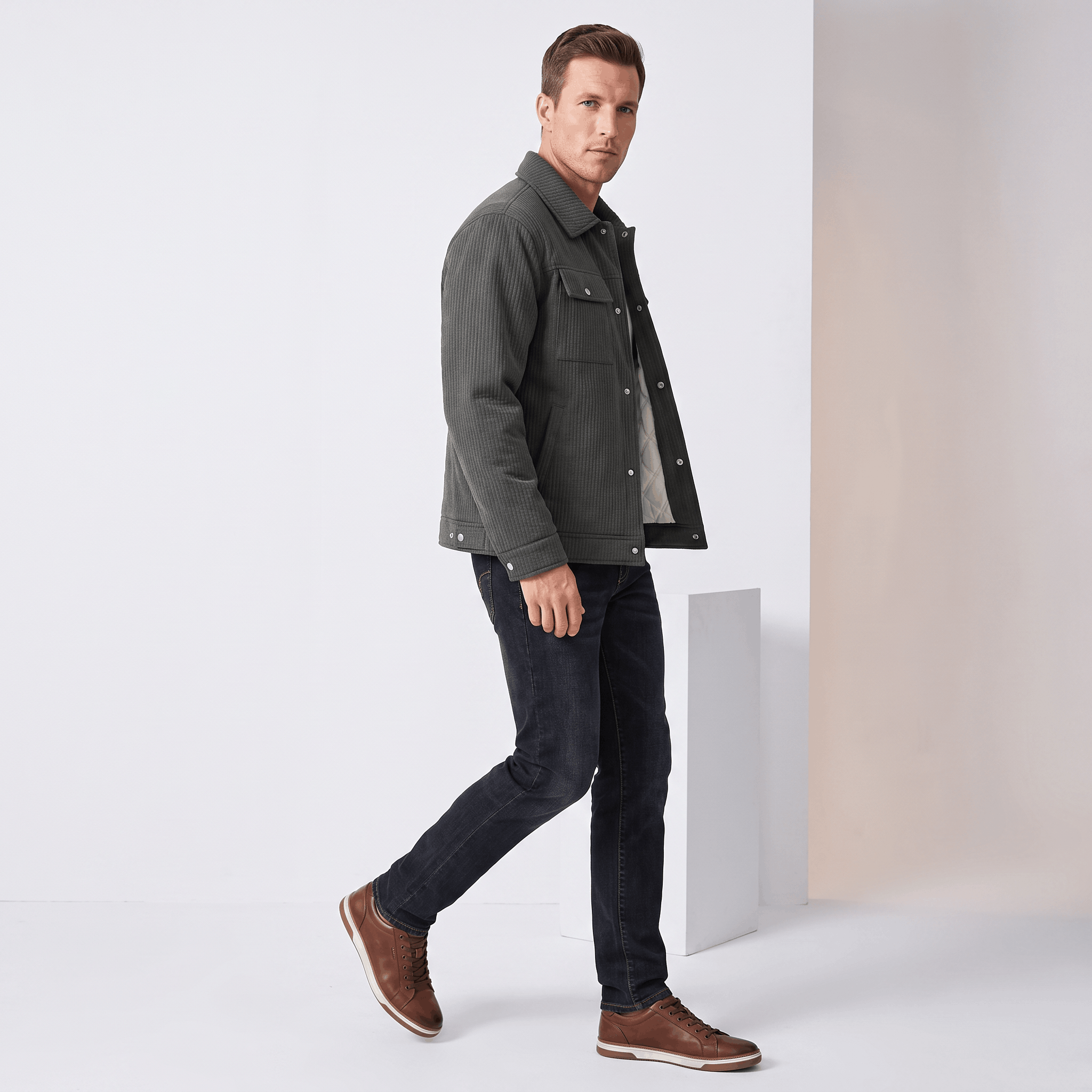 Dark grey corduroy trucker jacket with snap buttons, dual chest pockets, and diamond-quilted lining worn with black jeans.