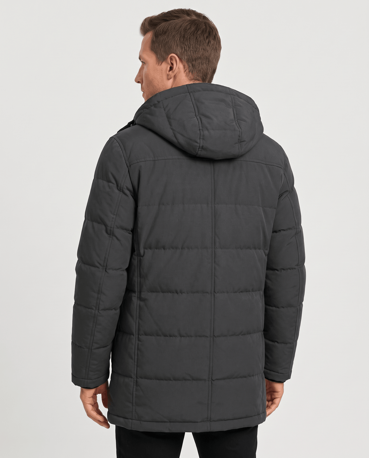 A man wearing a dark gray insulated winter parka with a hood and multiple utility pockets, shown from the back