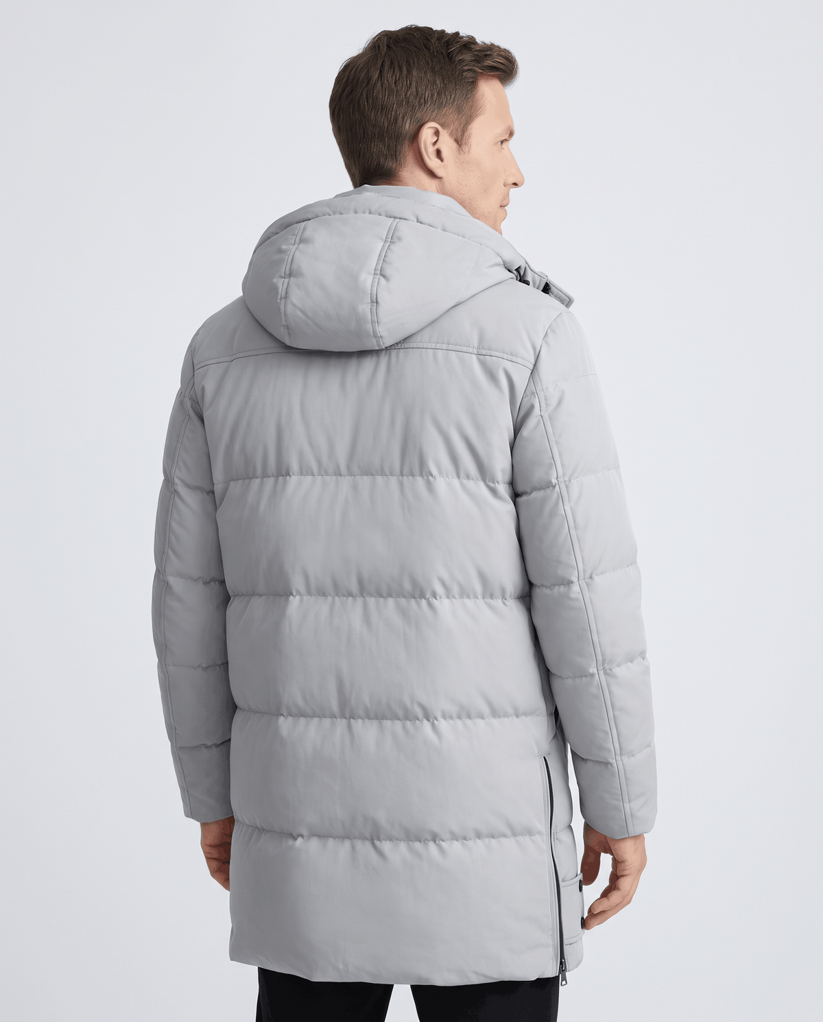 A man wearing a light gray padded longline winter parka with a hood, shown from the back