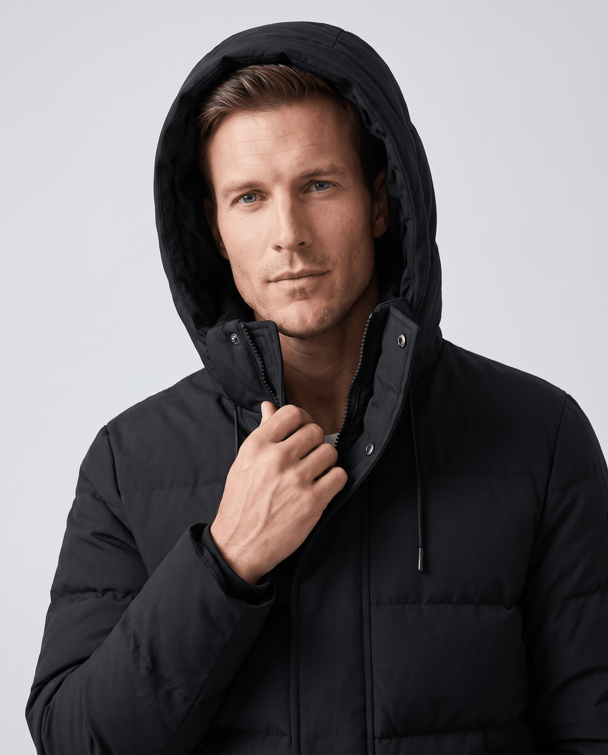 Close-up of a man wearing a black insulated winter parka, showing the hood and padded shell