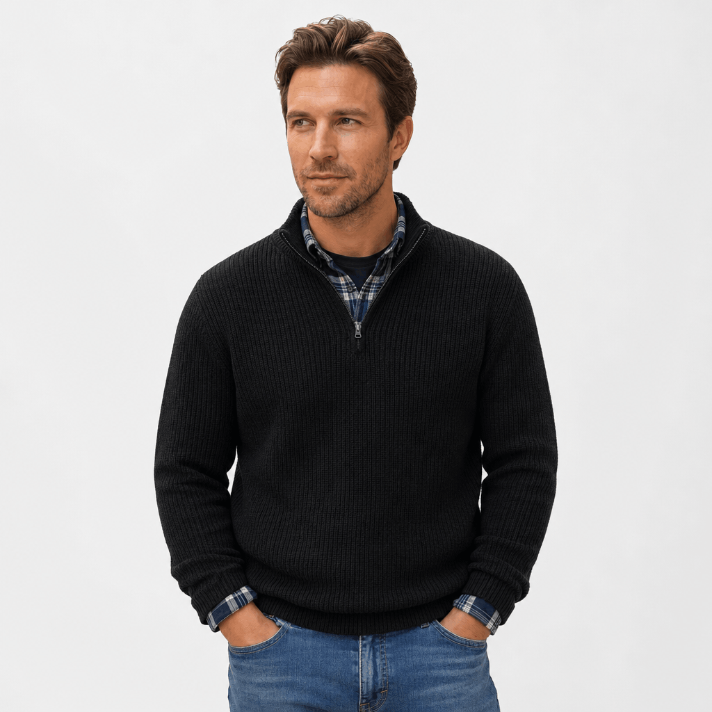 Man wearing a black ribbed knit quarter-zip sweater over a blue shirt, paired with blue jeans.