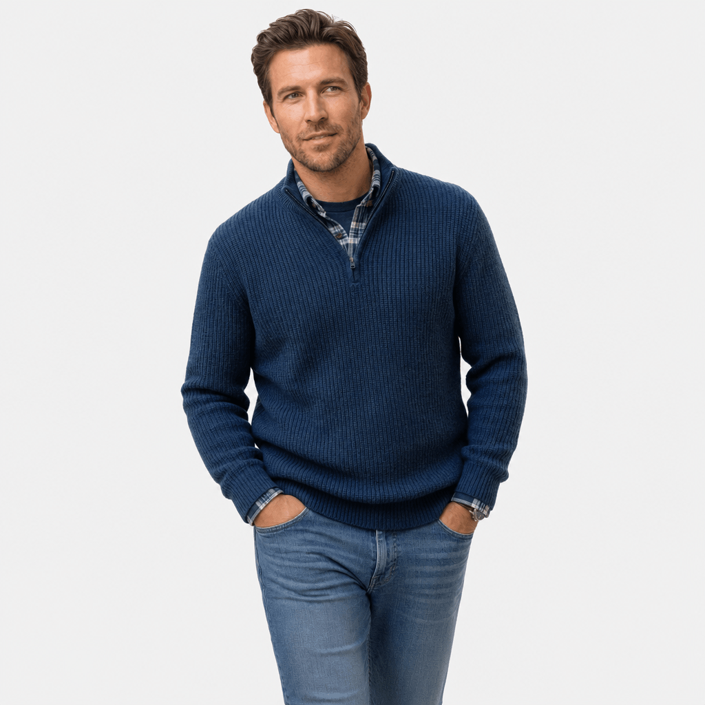 Man wearing a navy blue ribbed knit quarter-zip sweater over a blue shirt, paired with blue jeans.