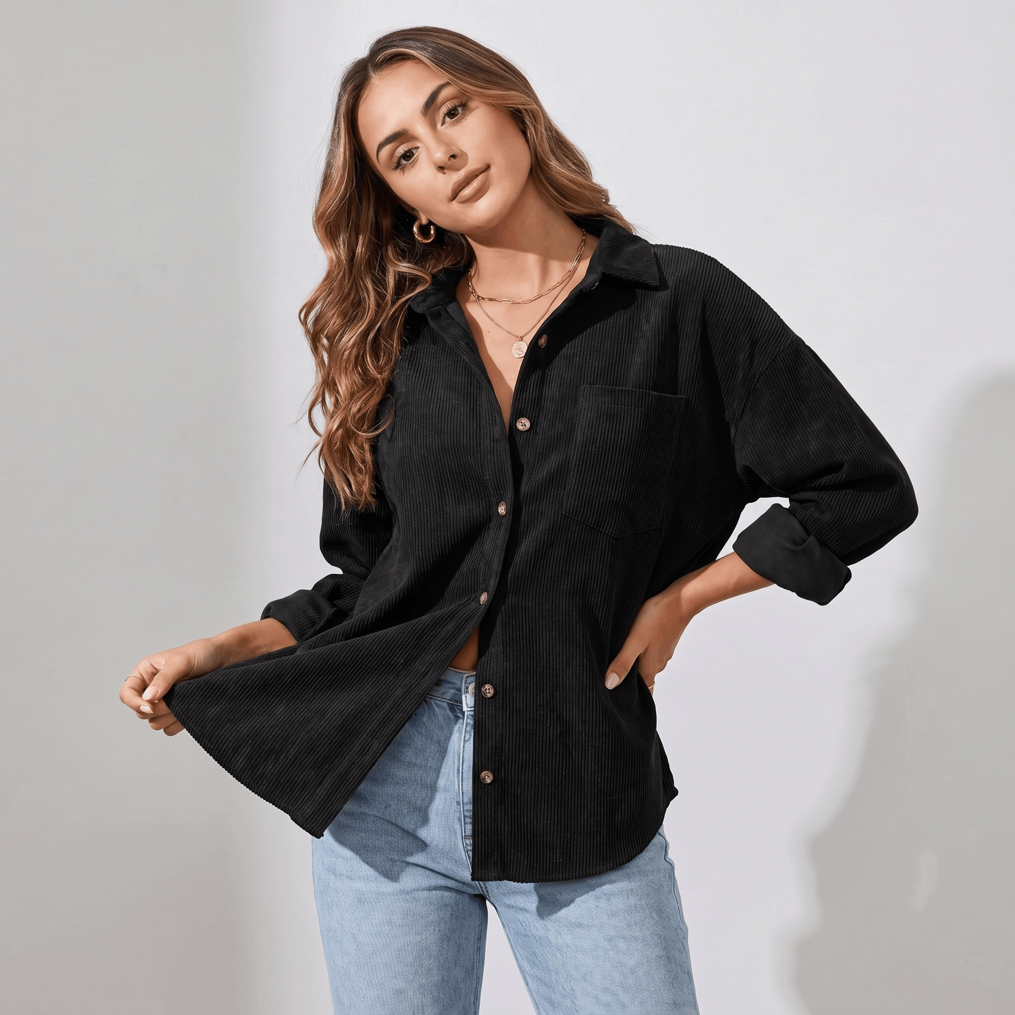 Oversized black corduroy button-down shirt with a point collar, drop shoulders, and rolled cuffs worn with light jeans.