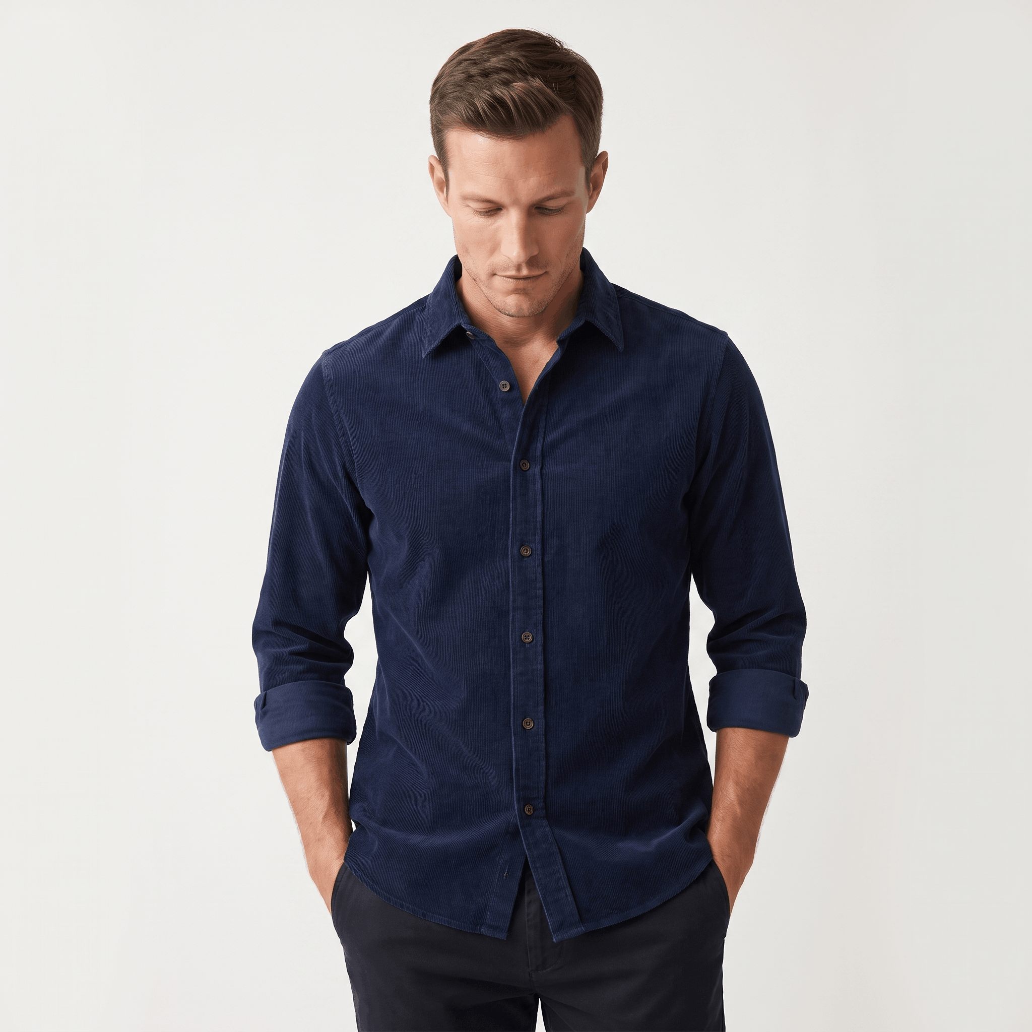 Navy blue slim-fit corduroy shirt with a clean front, classic collar, and rolled-up sleeves on a man.