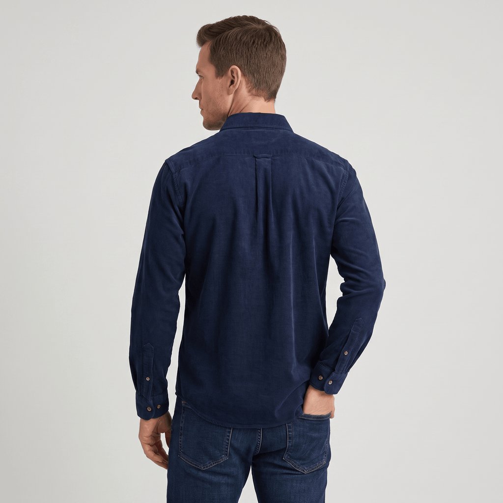 Navy blue slim-fit corduroy shirt with a classic collar and tailored back yoke, worn tucked into dark denim jeans.