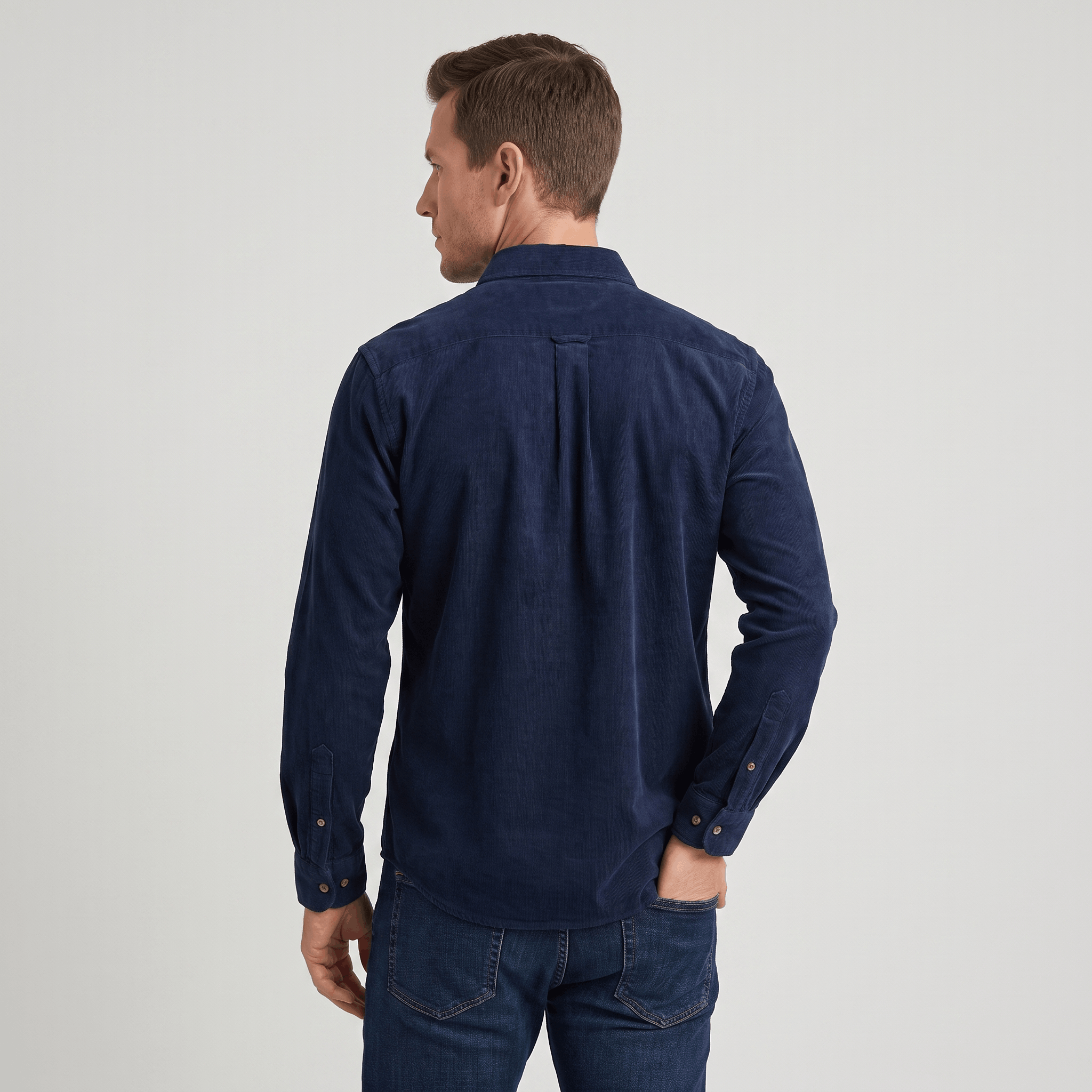 Navy blue slim-fit corduroy shirt with a classic collar and tailored back yoke, worn tucked into dark denim jeans.