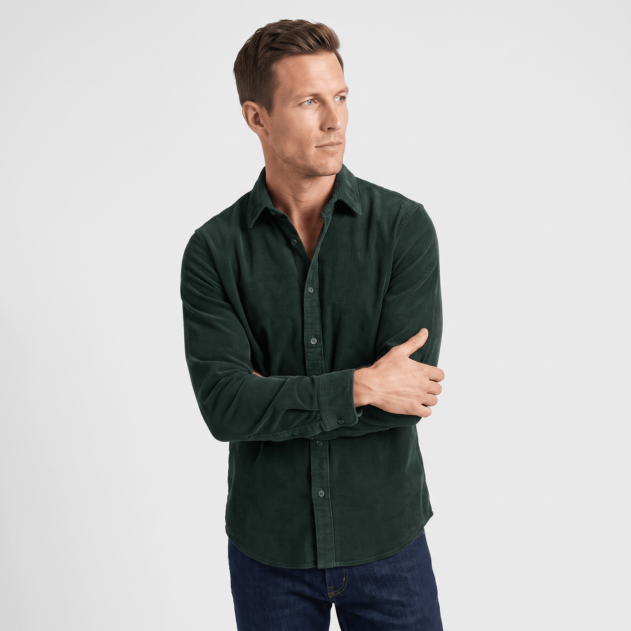 Slim-fit dark green corduroy button-up shirt with a clean front and classic collar, worn with dark denim jeans.