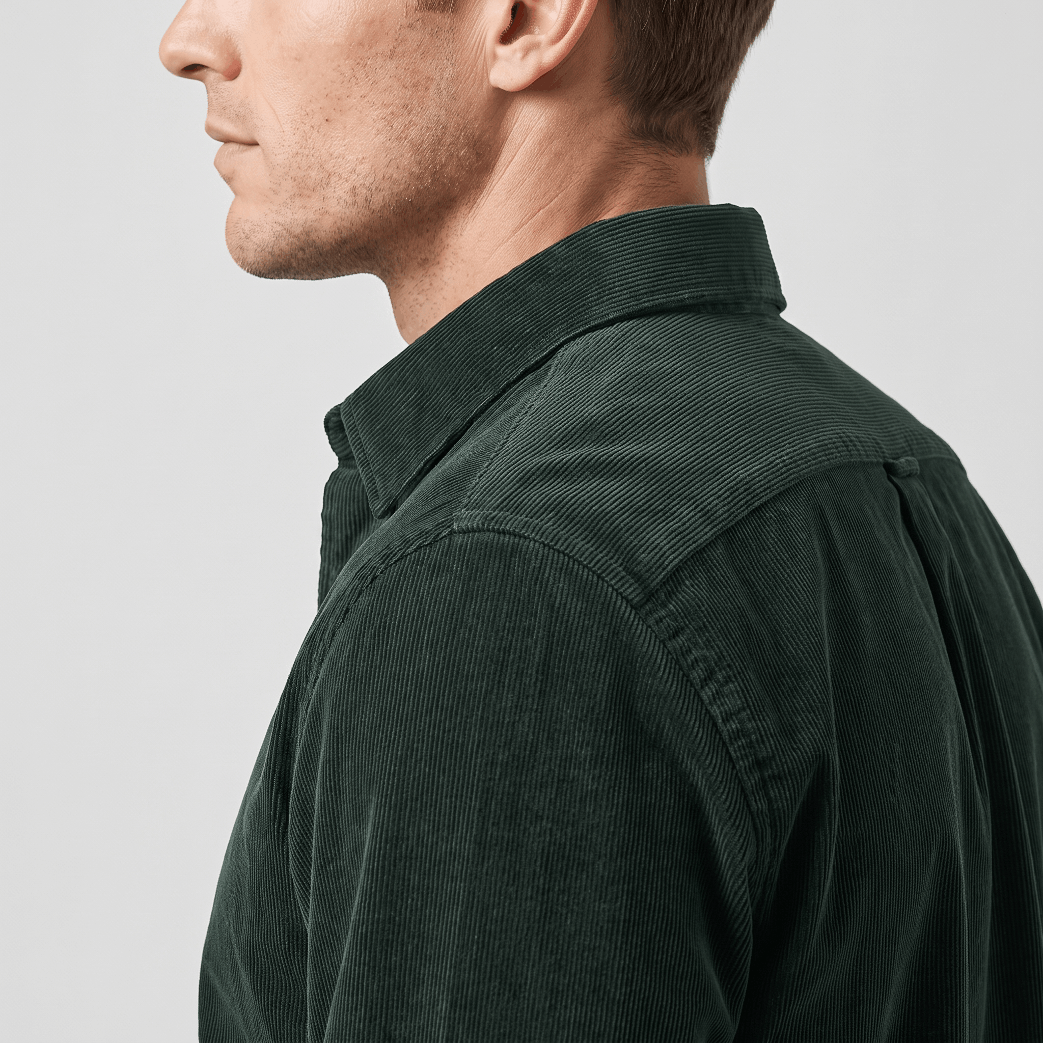Dark green slim-fit corduroy shirt with a classic collar and clean front, shown in profile on a man.