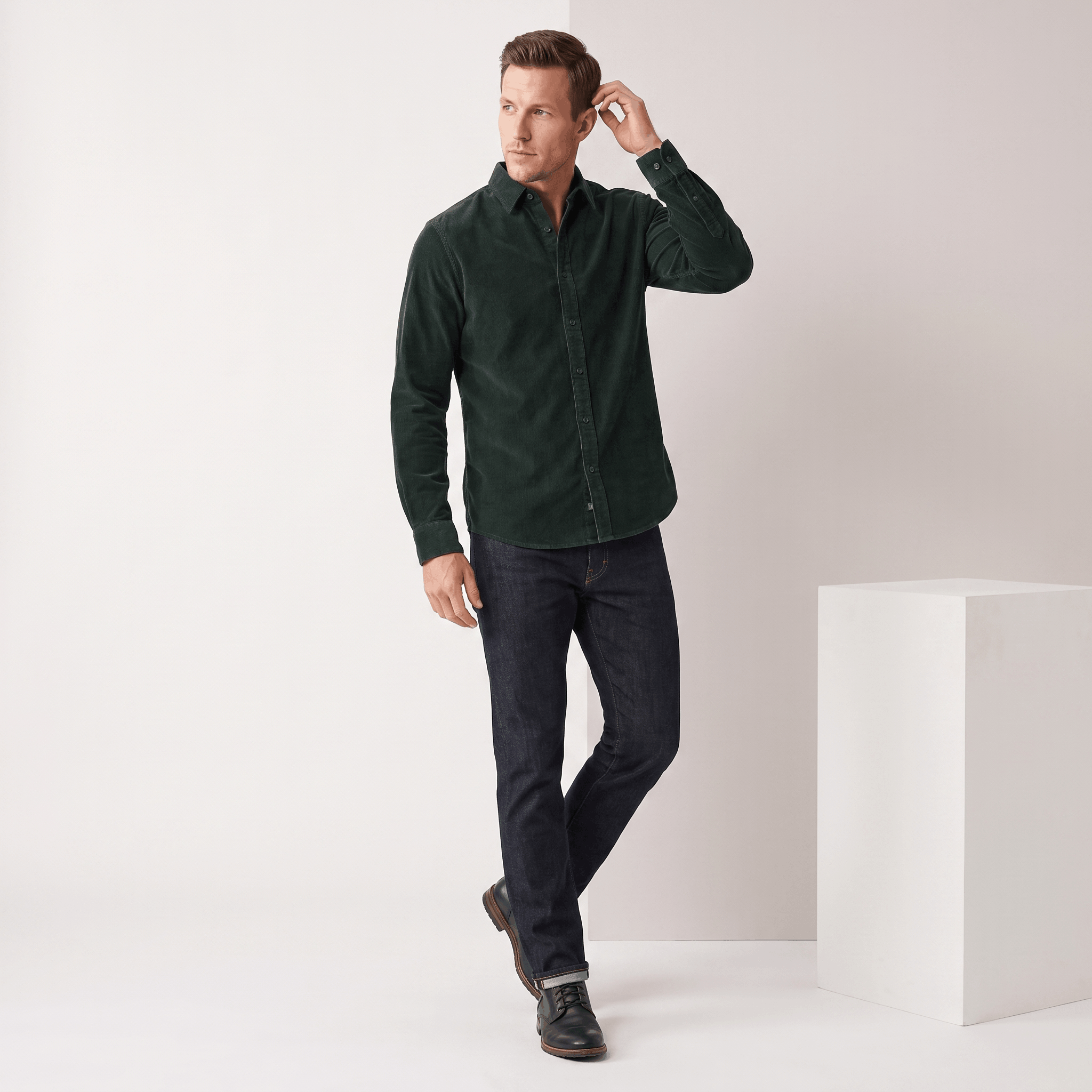 Slim-fit dark green corduroy shirt with a clean, pocketless front and classic collar, styled with dark denim jeans.