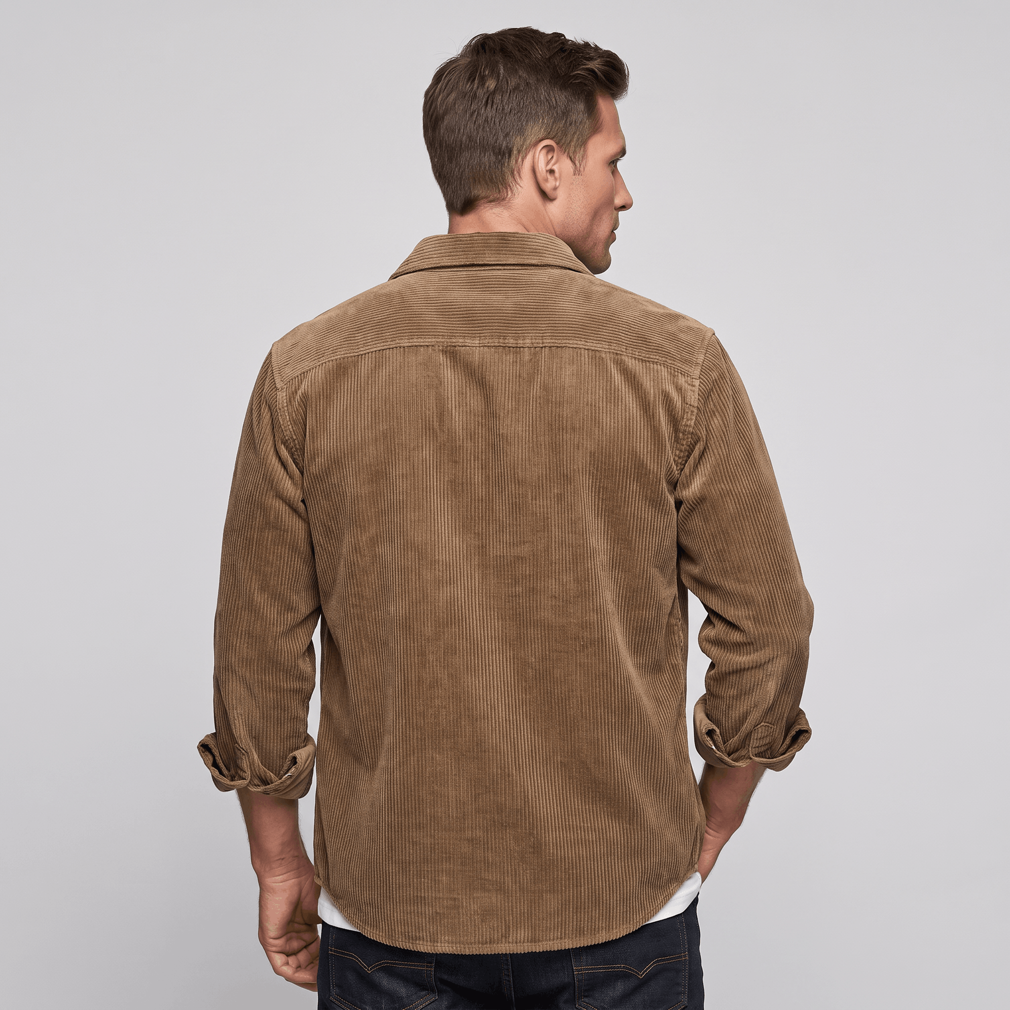Brown corduroy long-sleeve shirt with broad ribbing and a relaxed fit, worn over a white tee against a neutral background.