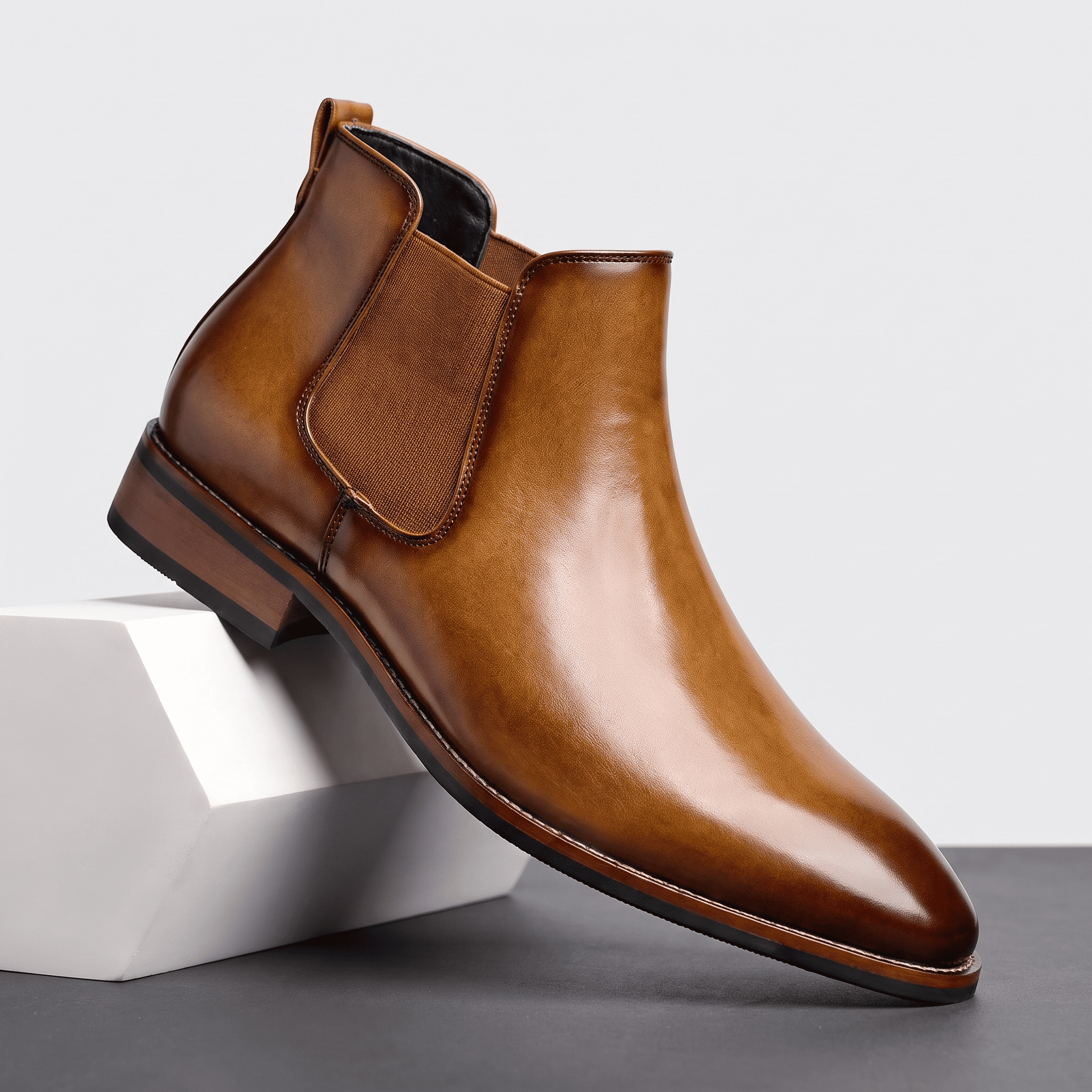 Polished brown leather Chelsea boot with elastic side panels, pull tabs, stitched detailing, and a low stacked heel.