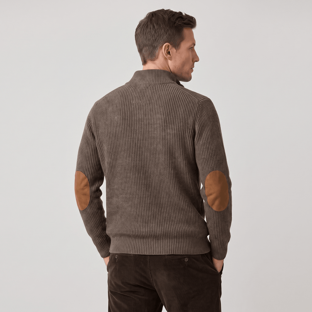 Brown vertical ribbed knit sweater with contrast elbow patches and a stand collar, worn with dark corduroy trousers.