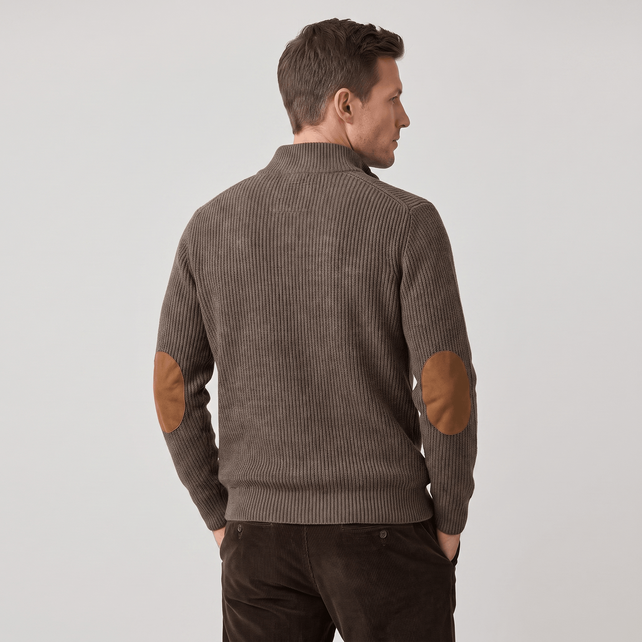Brown vertical ribbed knit sweater with contrast elbow patches and a stand collar, worn with dark corduroy trousers.