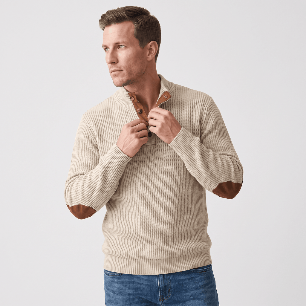 Beige ribbed knit henley sweater with a snap stand collar and brown contrast elbow patches, worn with blue denim jeans.