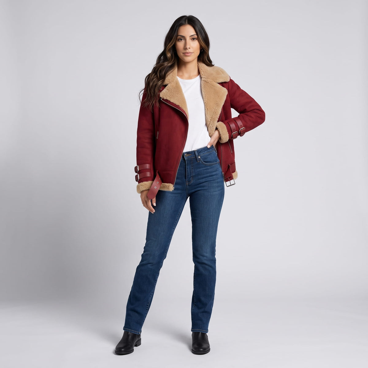A woman wearing a burgundy leather shearling aviator jacket with an asymmetric zip and buckled strap