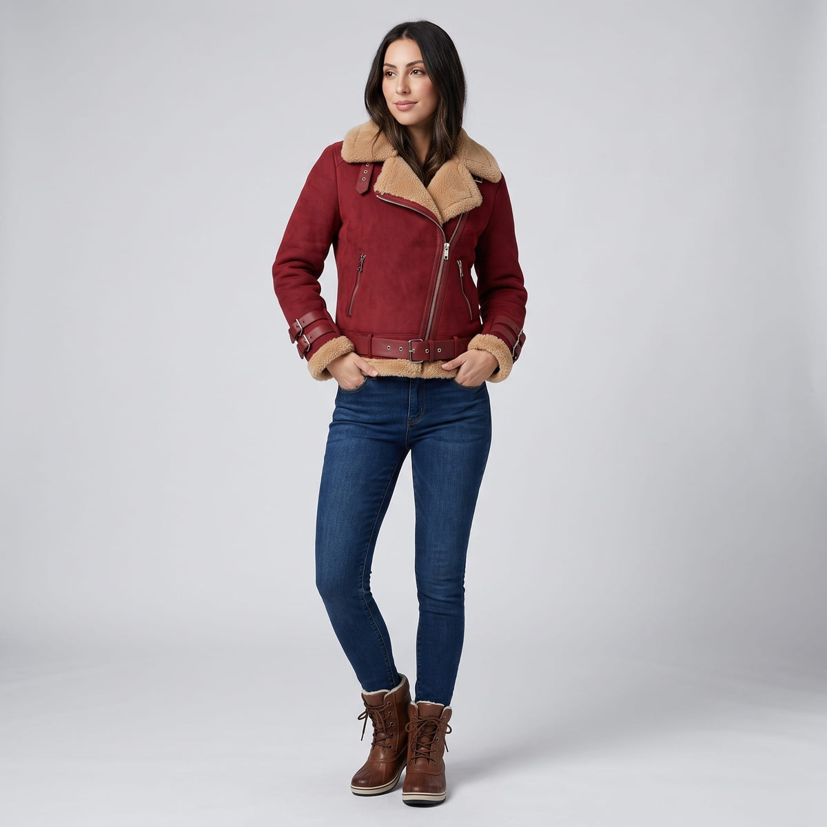 A woman wearing a burgundy leather shearling aviator jacket with an asymmetric zip and buckled strap, front view