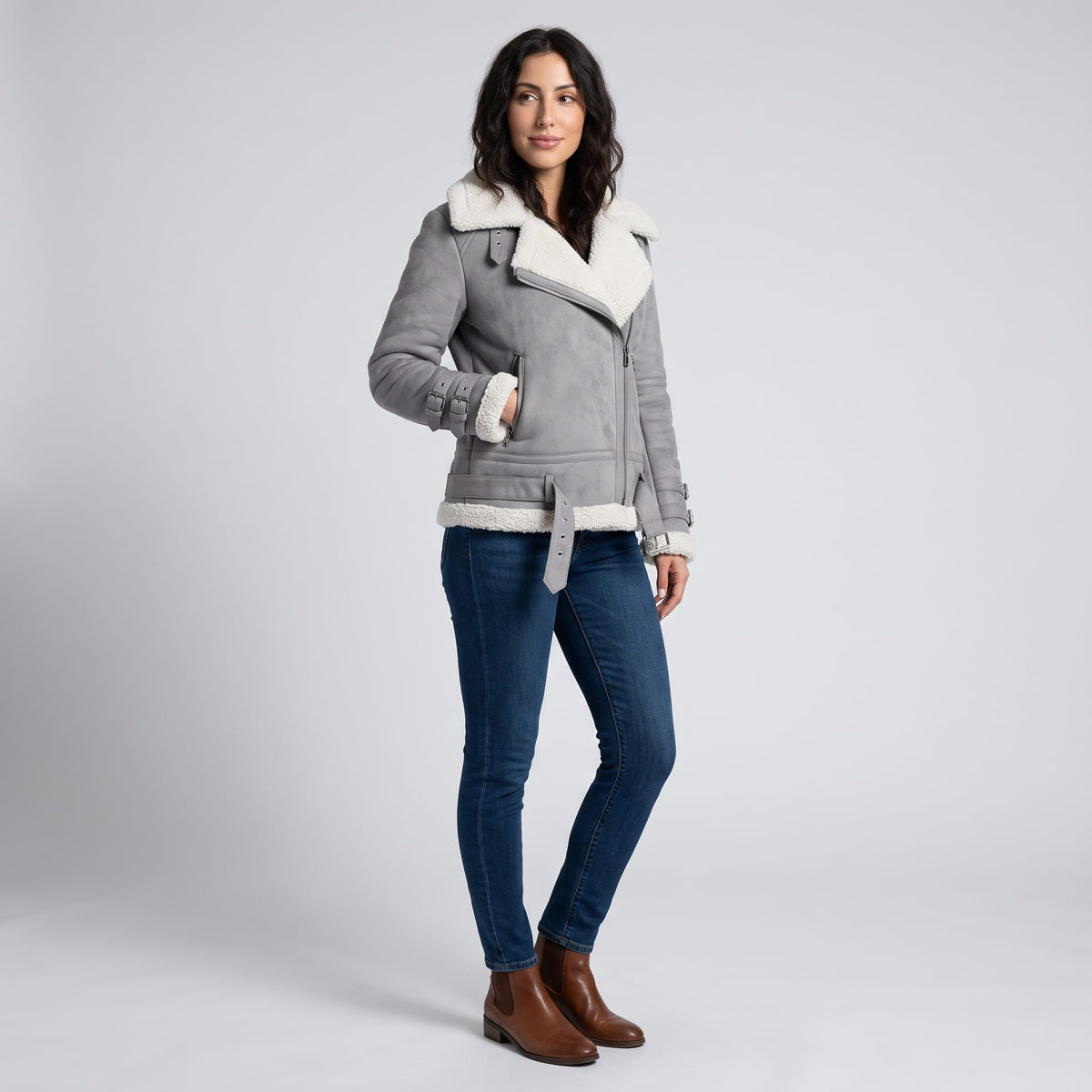 A woman wearing a gray leather shearling aviator jacket with an asymmetric zip and buckled strap