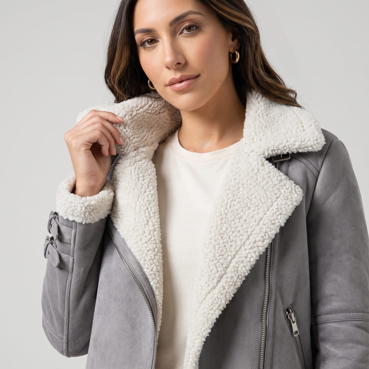 Close-up of a woman wearing a gray leather shearling aviator jacket, showing the plush collar and buckled strap