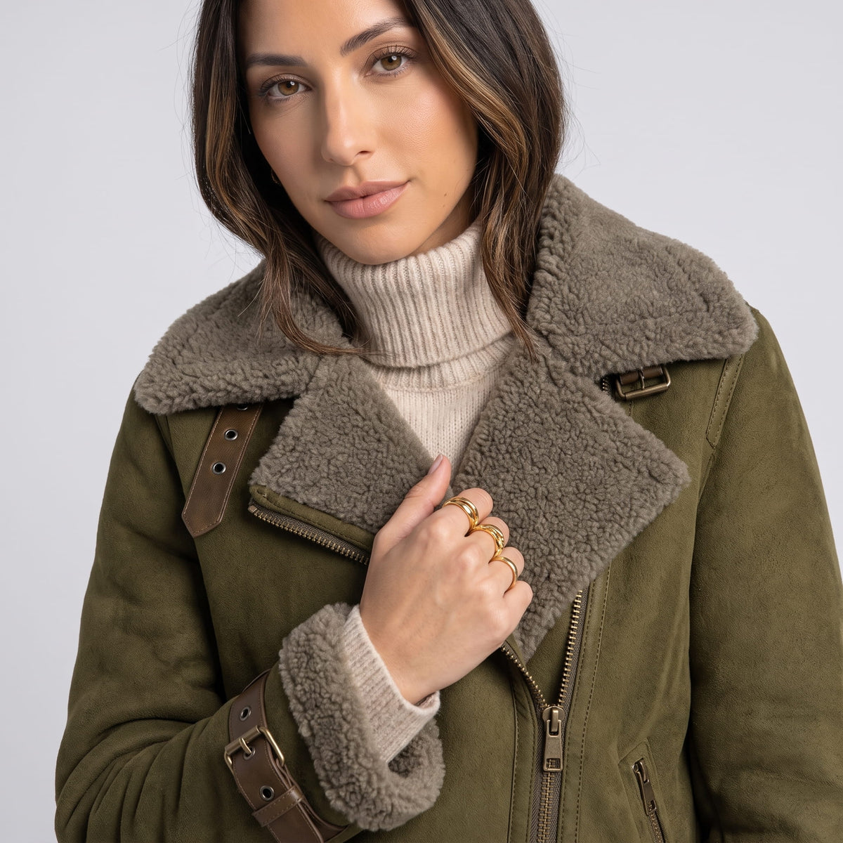 Close-up of an olive green leather shearling aviator jacket showing the plush collar and asymmetric zip