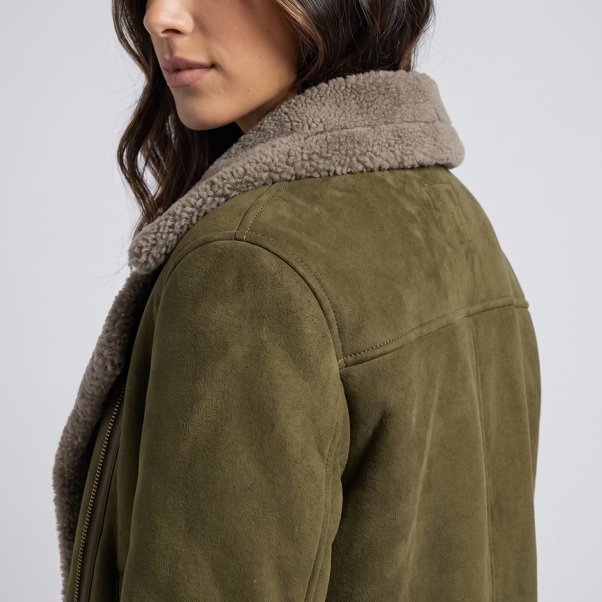 Close-up of an olive green leather shearling aviator jacket showing the plush shearling collar and back detail