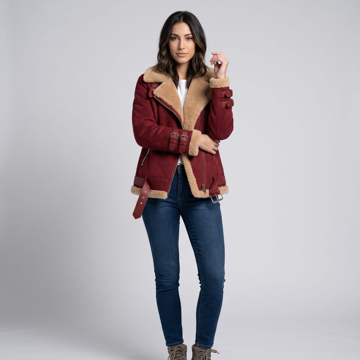 A woman wearing a burgundy leather shearling aviator jacket with an asymmetric zip and buckled strap