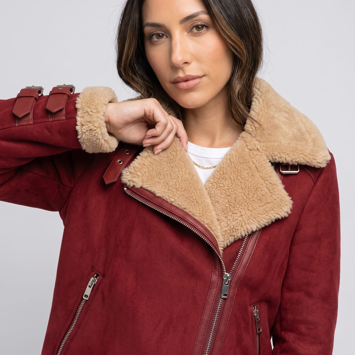 Close-up of a woman wearing a burgundy leather shearling aviator jacket, showing the plush shearling collar and zip front