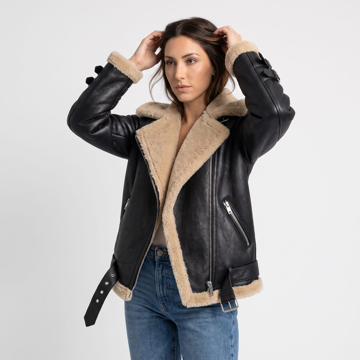 A woman wearing a black leather shearling aviator jacket with an asymmetric zip and buckled strap