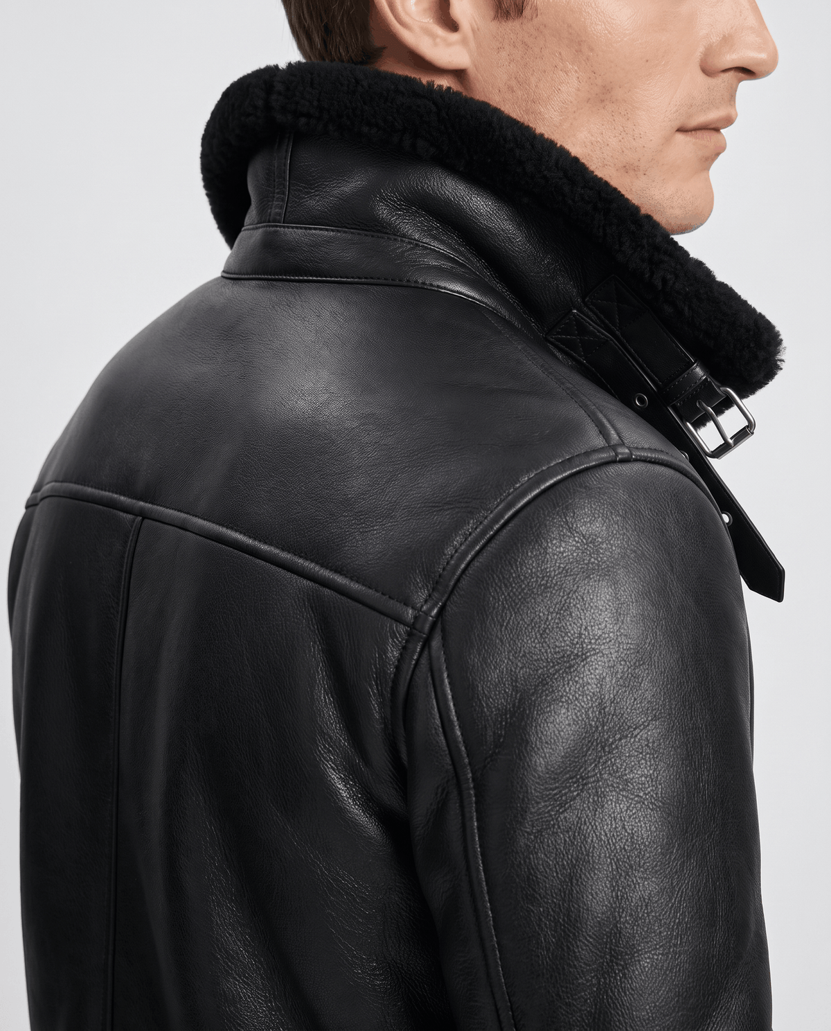 Close-up of a black leather shearling aviator jacket showing the plush collar and back detail