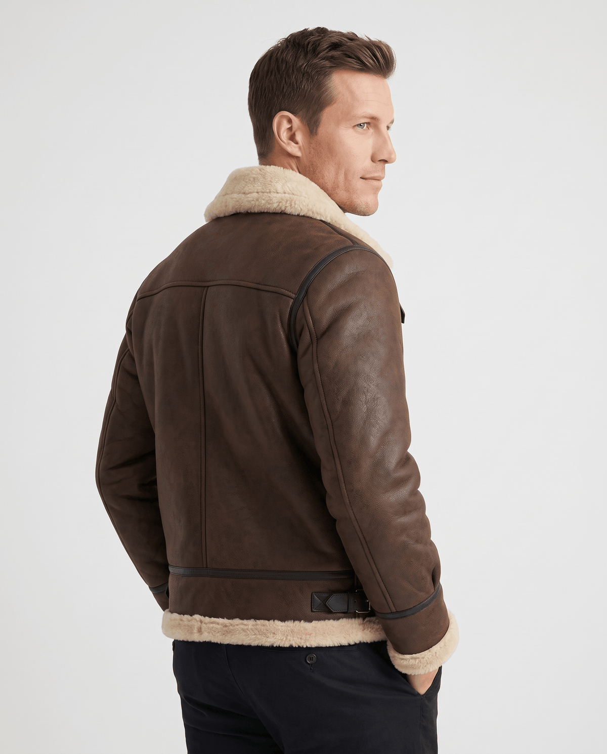 A man wearing a brown leather shearling aviator jacket with a buckle strap, shown from the back