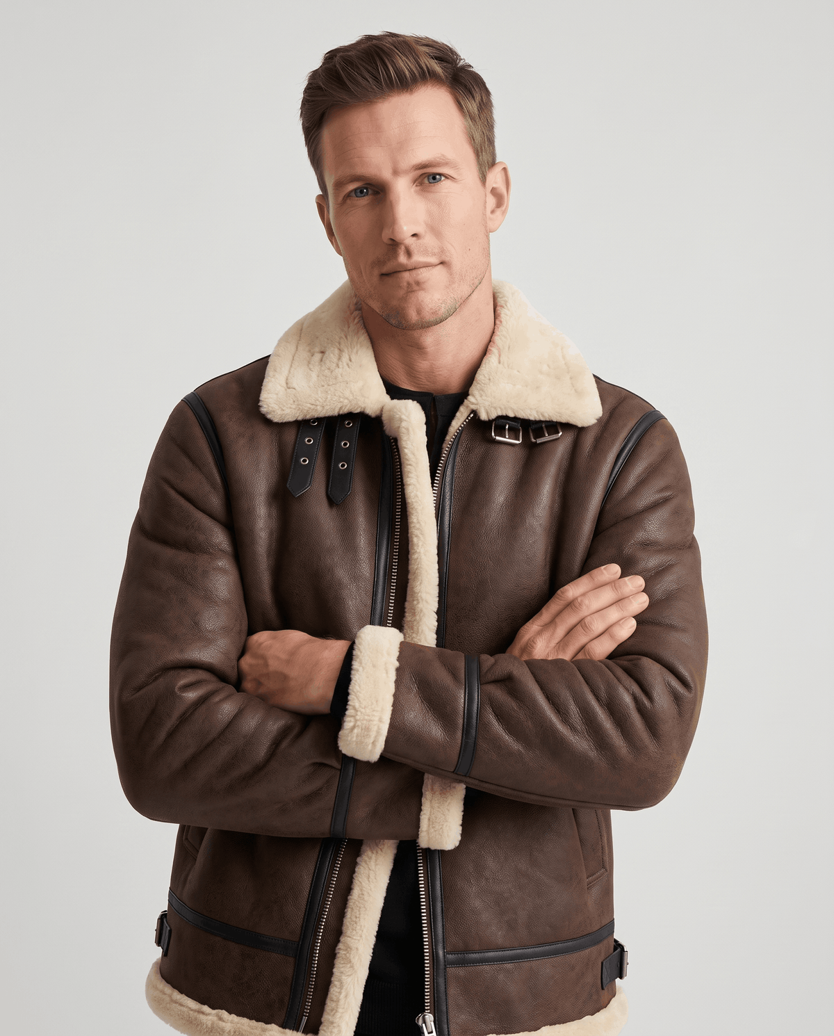 A man wearing a brown leather shearling aviator jacket with an asymmetrical zip and buckle strap