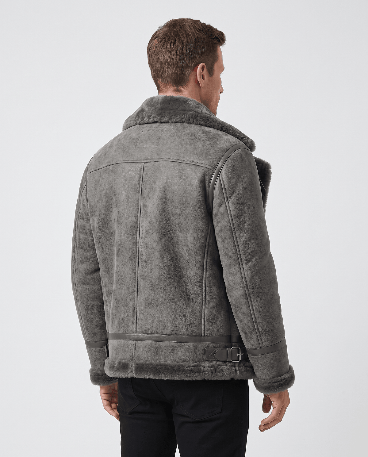 A man wearing a gray leather shearling aviator jacket with a distressed finish and lamb fur lining, shown from the back