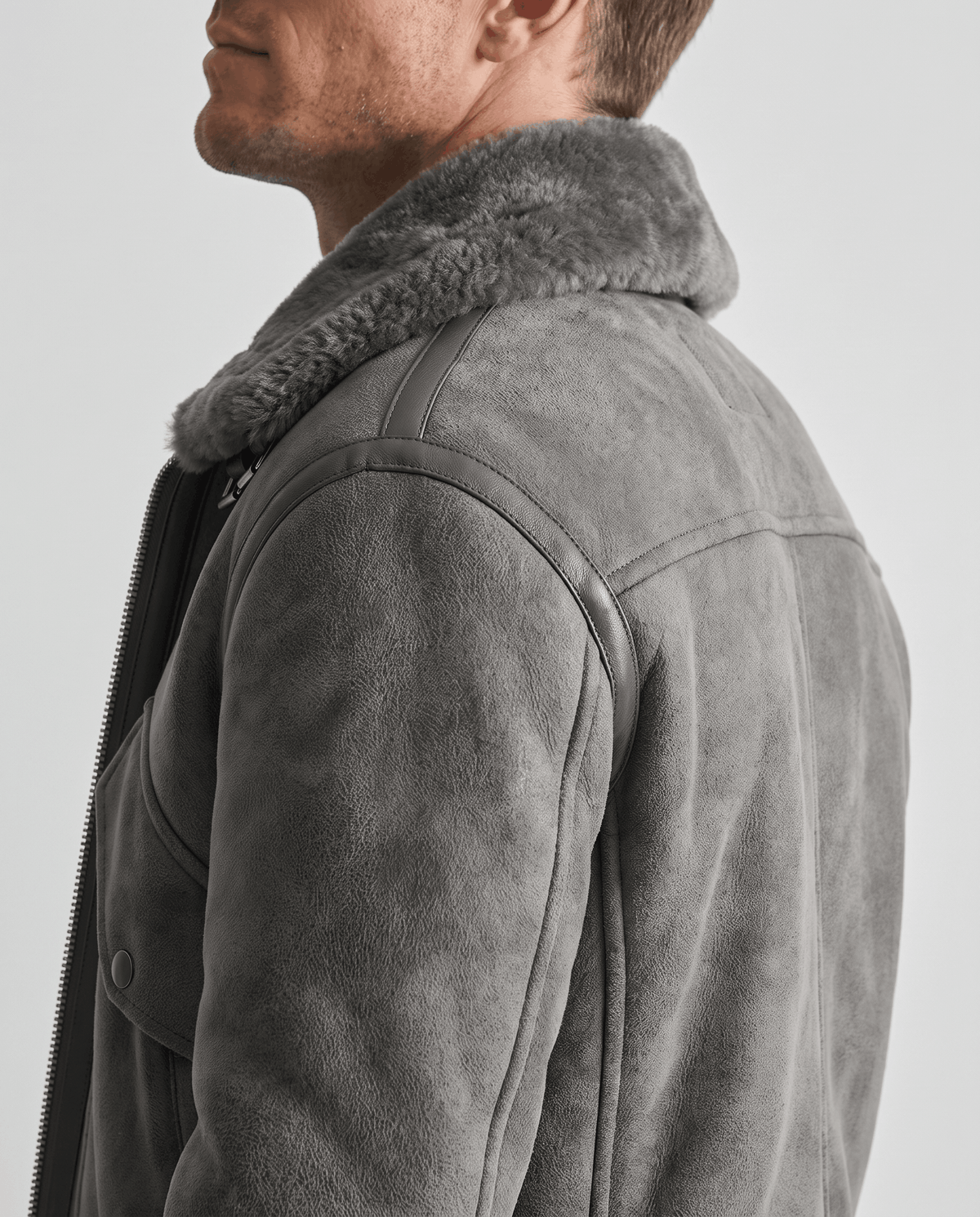 Close-up of a gray leather shearling aviator jacket showing the plush fur collar and distressed finish