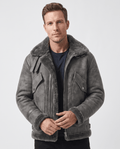 A man wearing a gray leather shearling aviator jacket with a distressed finish and lamb fur lining