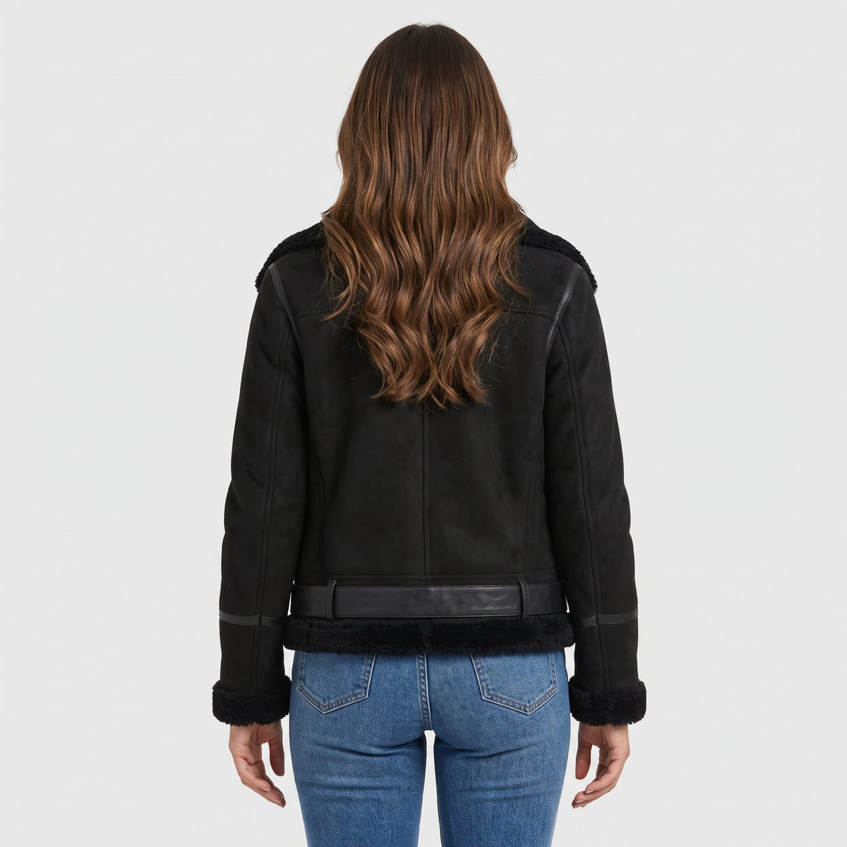 A woman wearing a black leather shearling aviator jacket with an oversized collar and belted waist, shown from the back