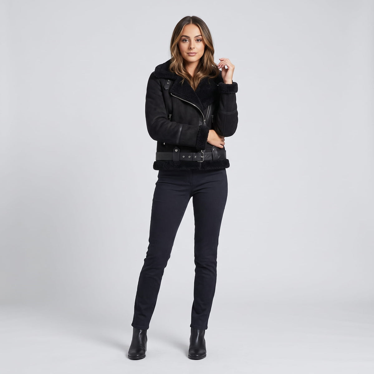 A woman wearing a black leather shearling aviator jacket with an oversized collar and belted waist, front view