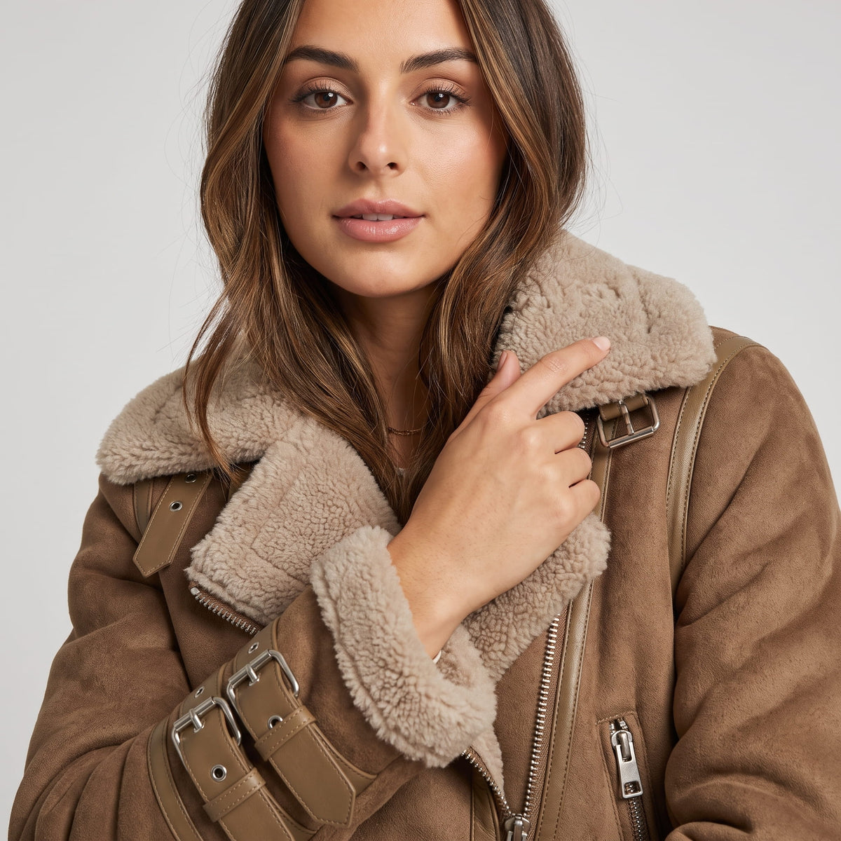 Close-up of a woman wearing a brown leather shearling aviator jacket, showing the oversized collar and belted waist