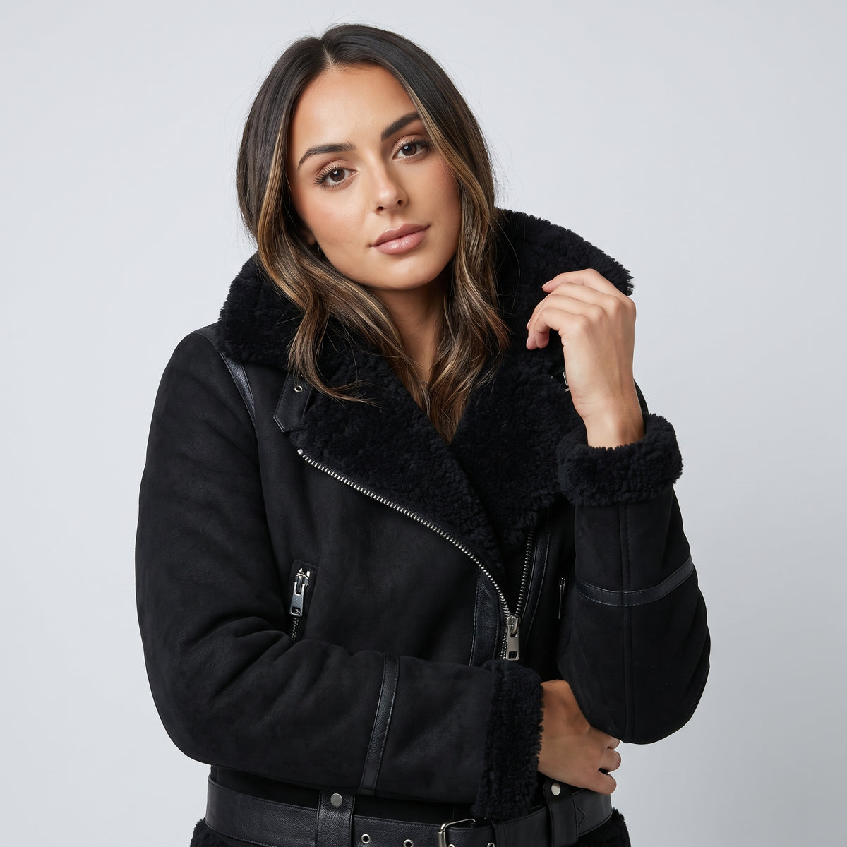A woman wearing a black leather shearling aviator jacket with an oversized collar and belted waist