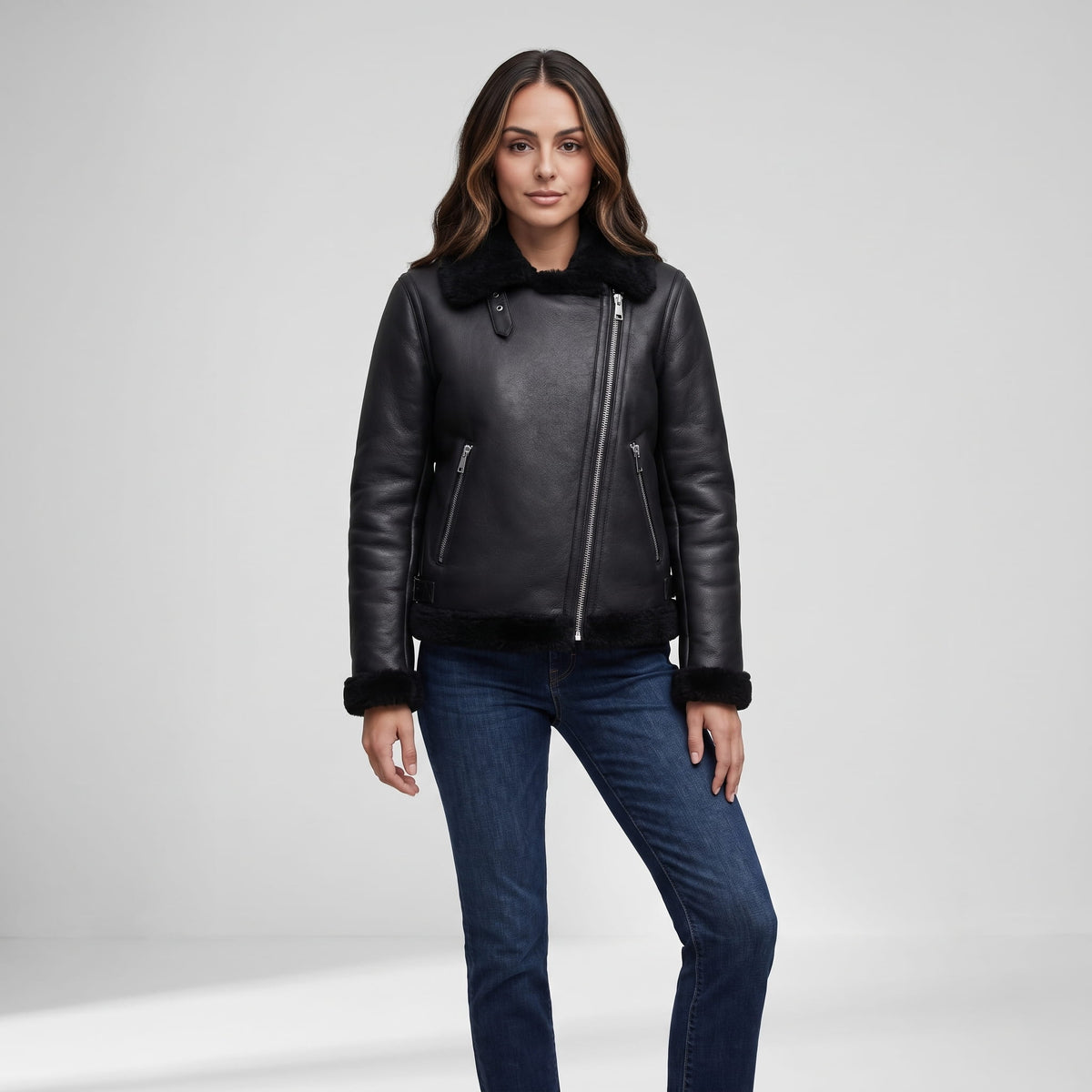 A woman wearing a black leather shearling biker jacket with an asymmetrical zip and plush trim, front view