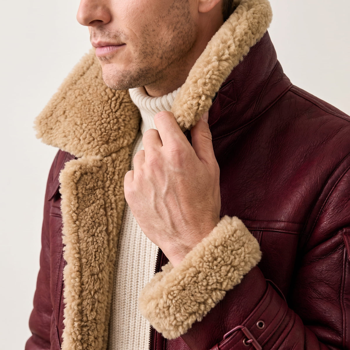 Close-up of a burgundy leather shearling bomber jacket showing the plush sherpa collar and zip front