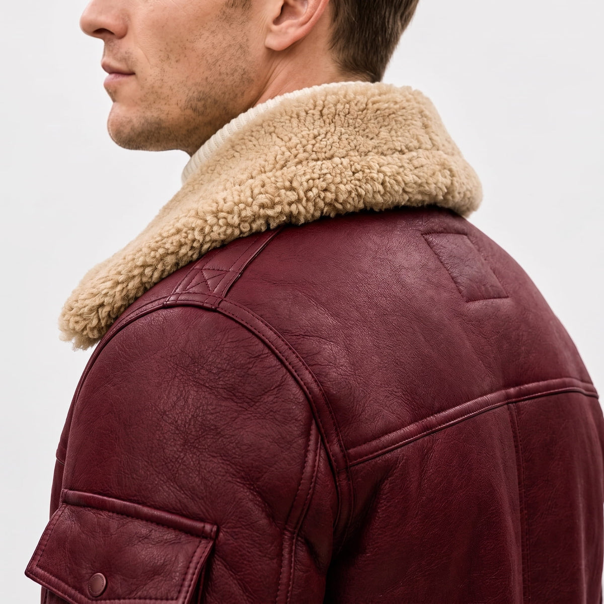 Close-up of a burgundy leather shearling bomber jacket showing the sherpa collar and shoulder detail