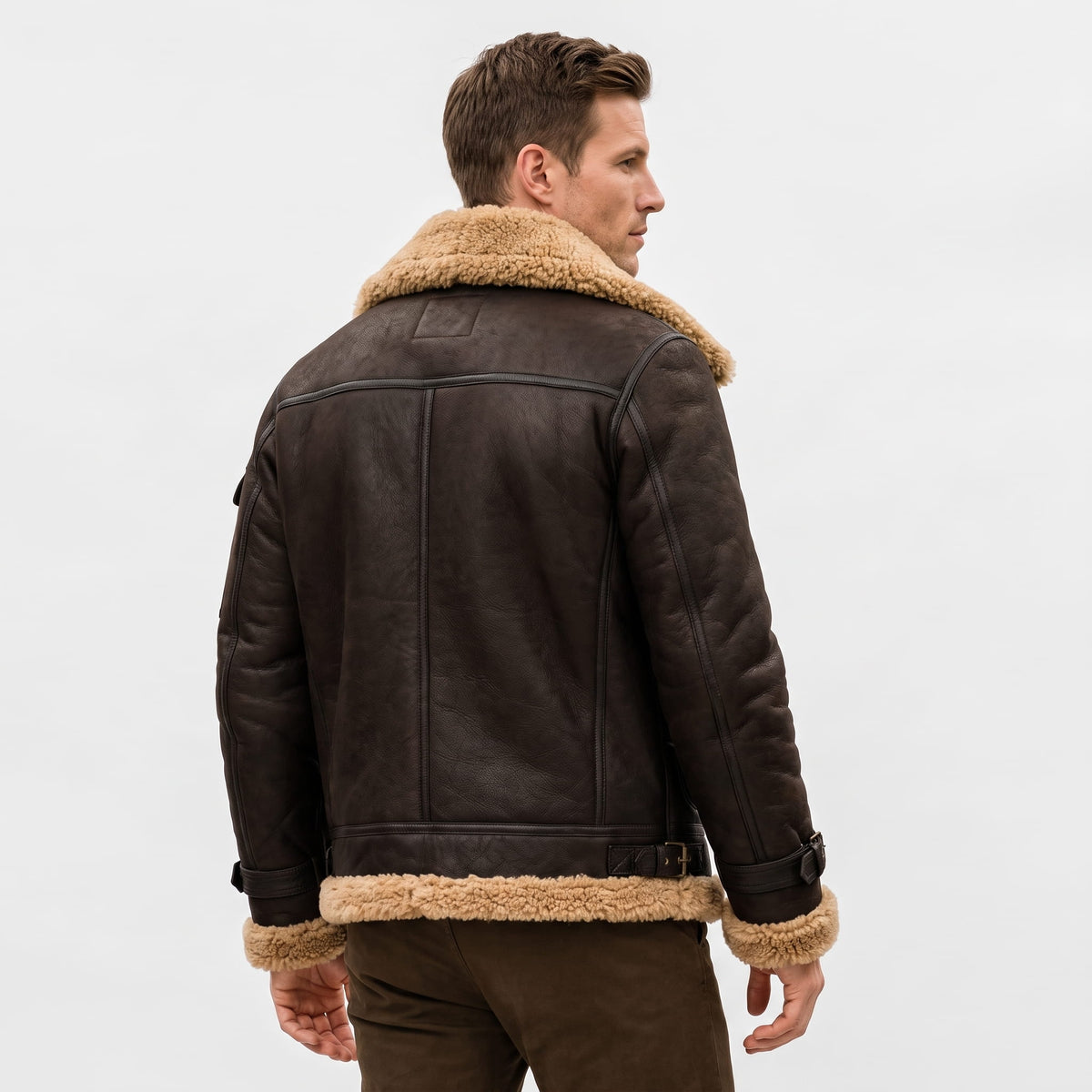 A man wearing a dark brown leather shearling bomber jacket with a sherpa collar, shown from the back