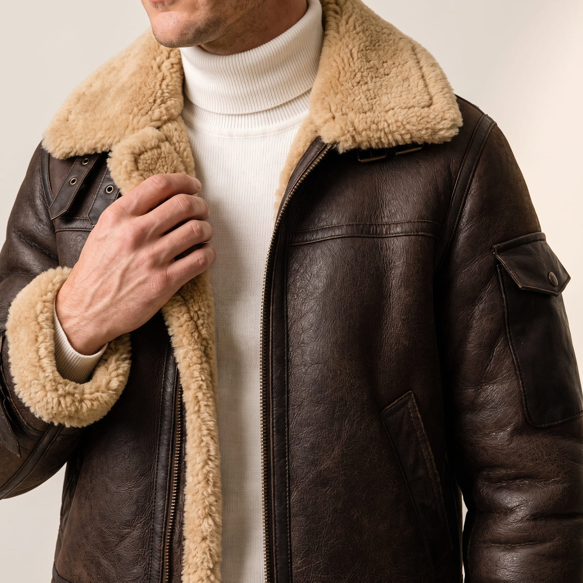 Close-up of a dark brown leather shearling bomber jacket showing the plush sherpa collar and front detail