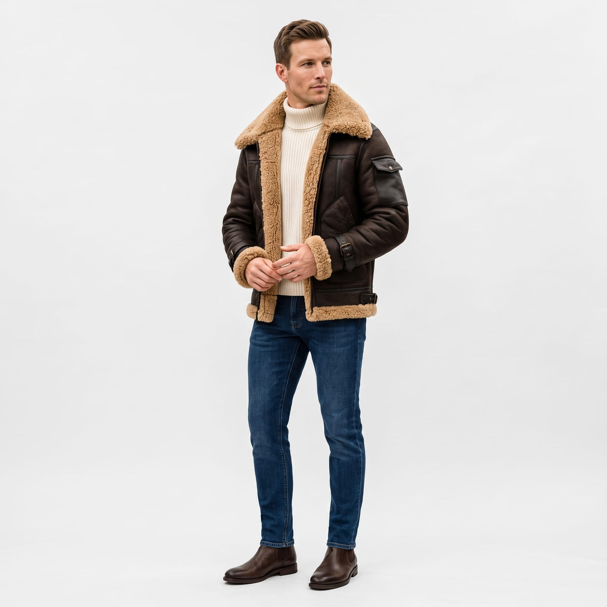 A man wearing a dark brown leather shearling bomber jacket with a sherpa collar and zip pockets, full-length view