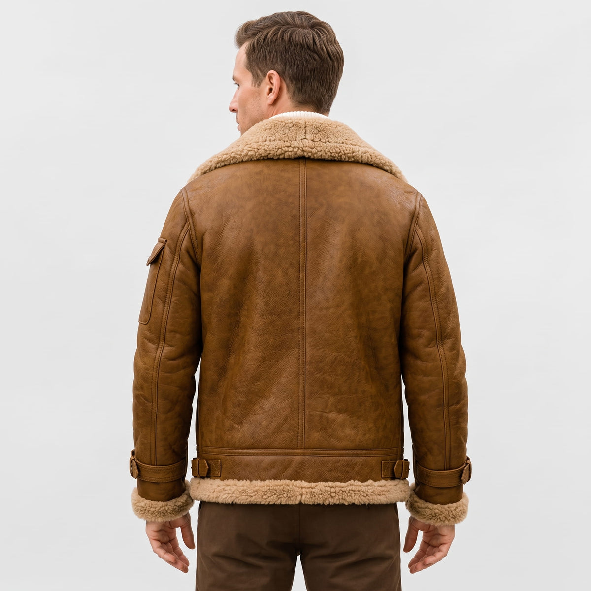 A man wearing a brown leather shearling bomber jacket with a sherpa collar, shown from the back