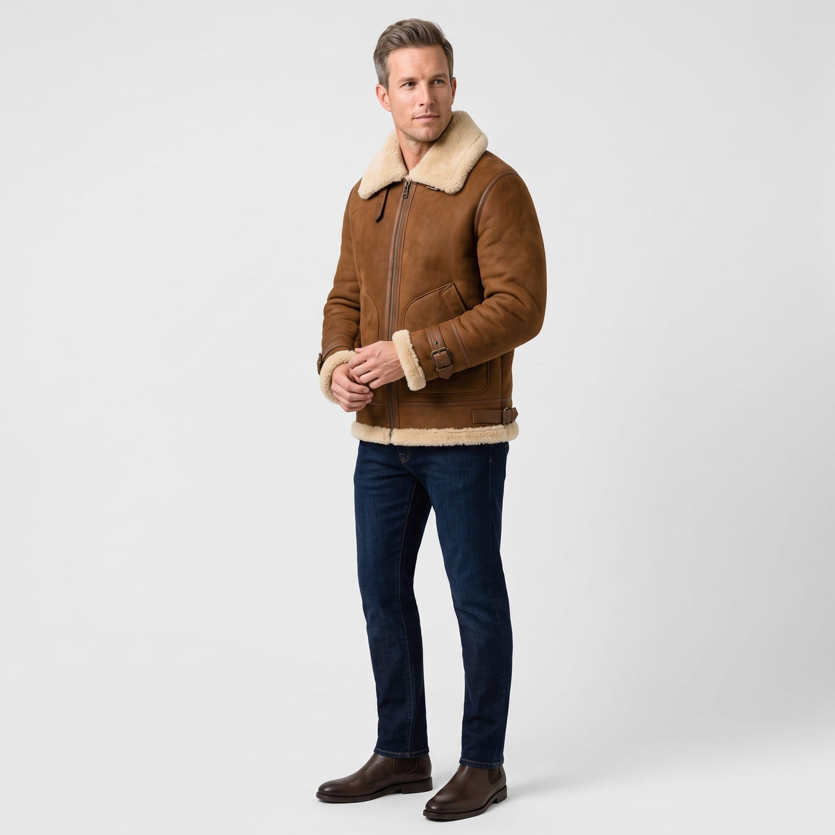 A man wearing a brown leather shearling bomber jacket with a sherpa collar and zip pockets, full-length view