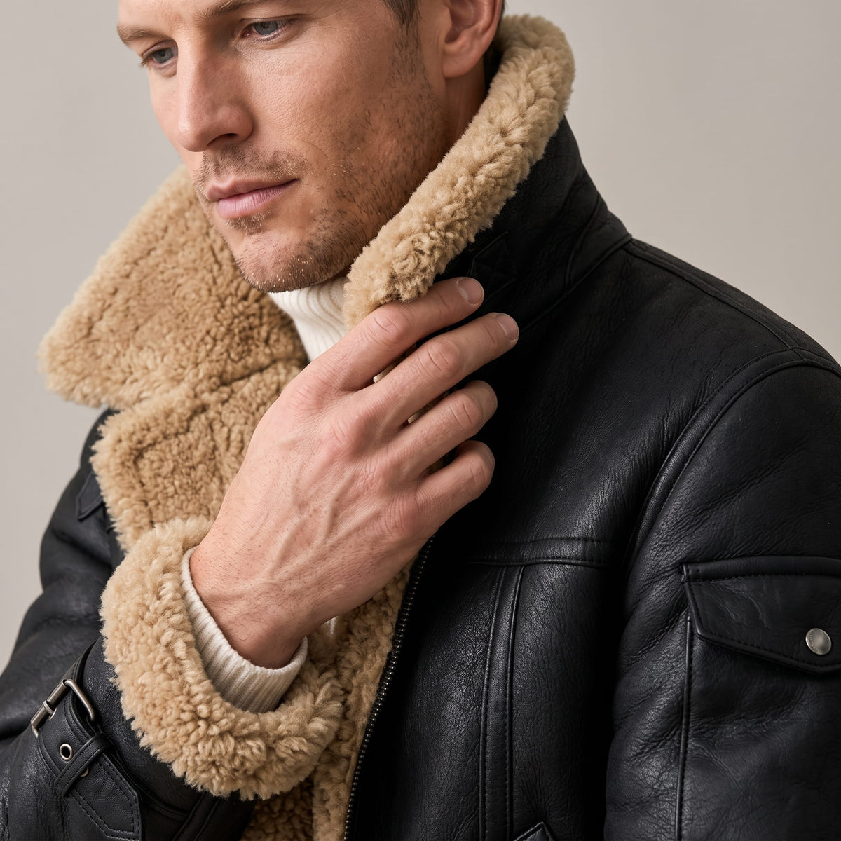 Close-up of a man wearing a black leather shearling bomber jacket, showing the sherpa collar and zip front