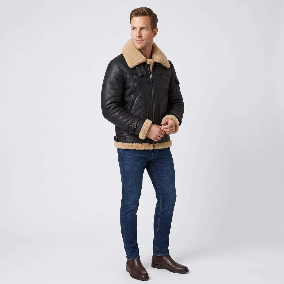A man wearing a black leather shearling bomber jacket with a sherpa collar and zip pockets, full-length view