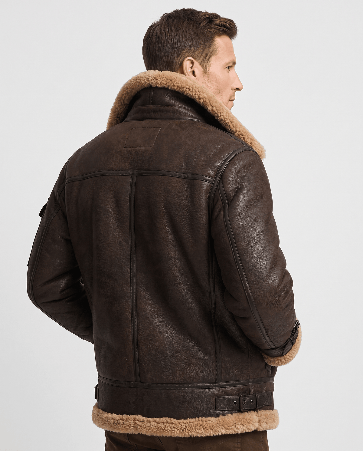 A man wearing a brown leather shearling jacket with fur lining and utility pockets, shown from the back