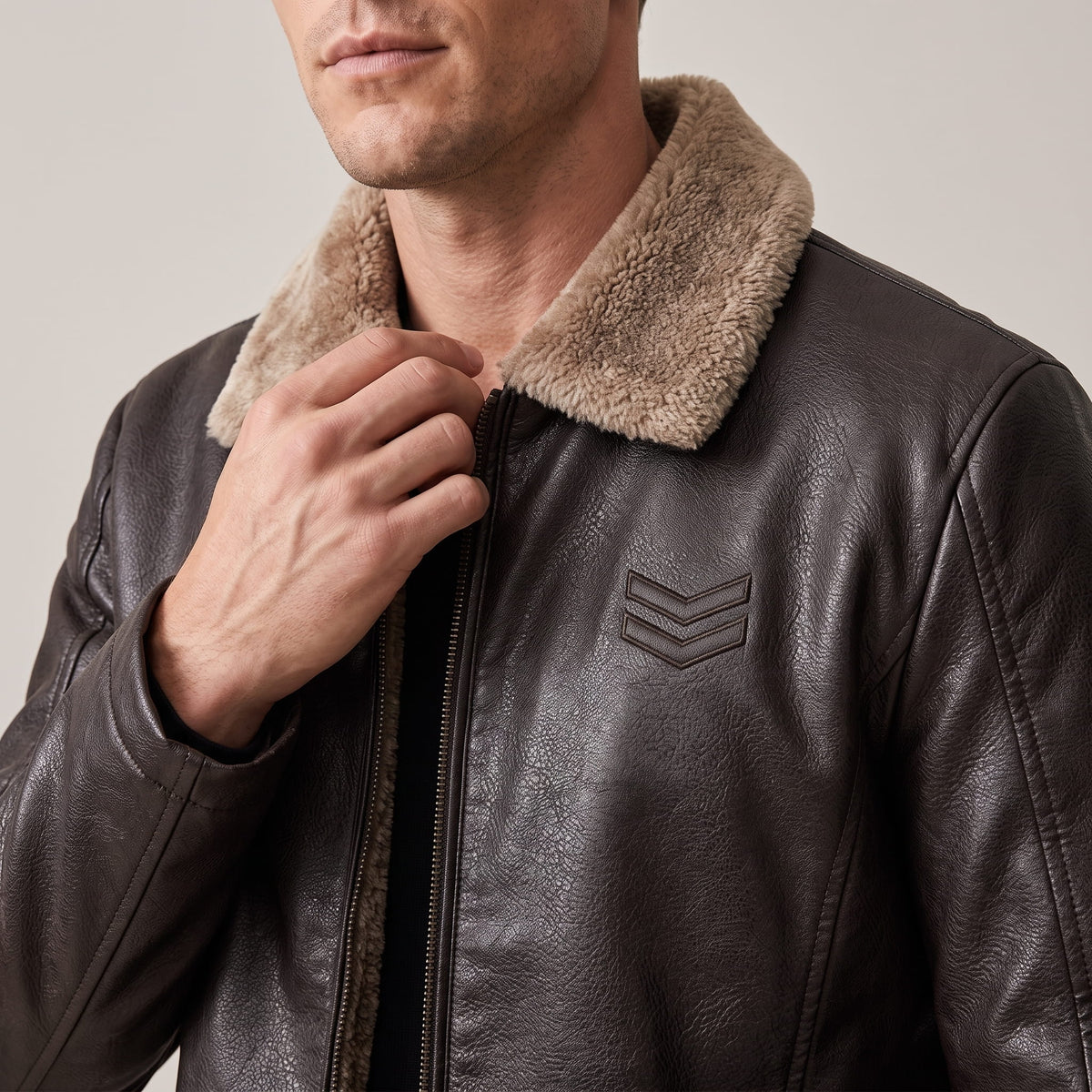 Close-up of a man wearing a dark brown leather shearling jacket, showing the plush collar and zip front